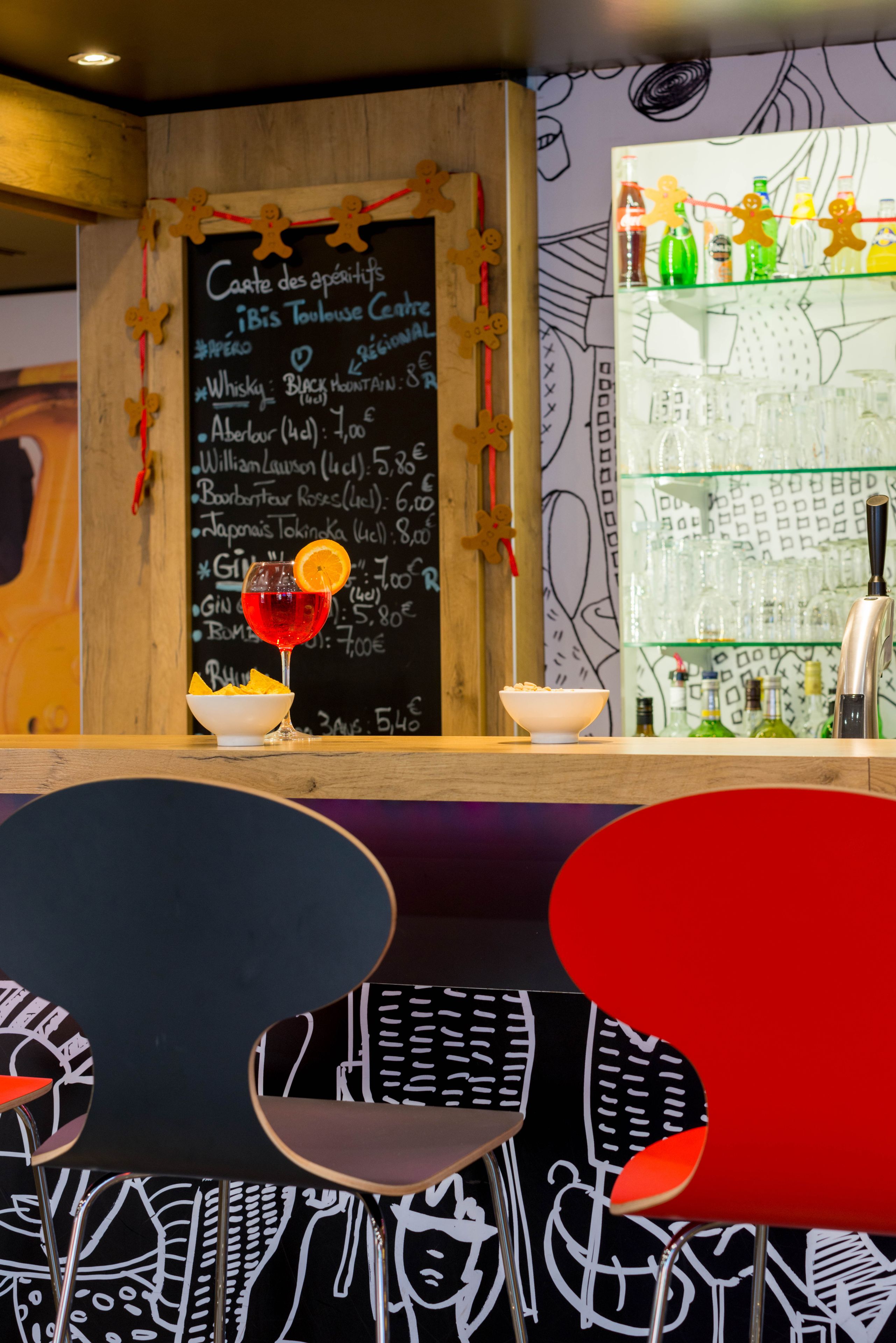 A bar area with a chalkboard menu, a glass of red drink, and a bowl of snacks.