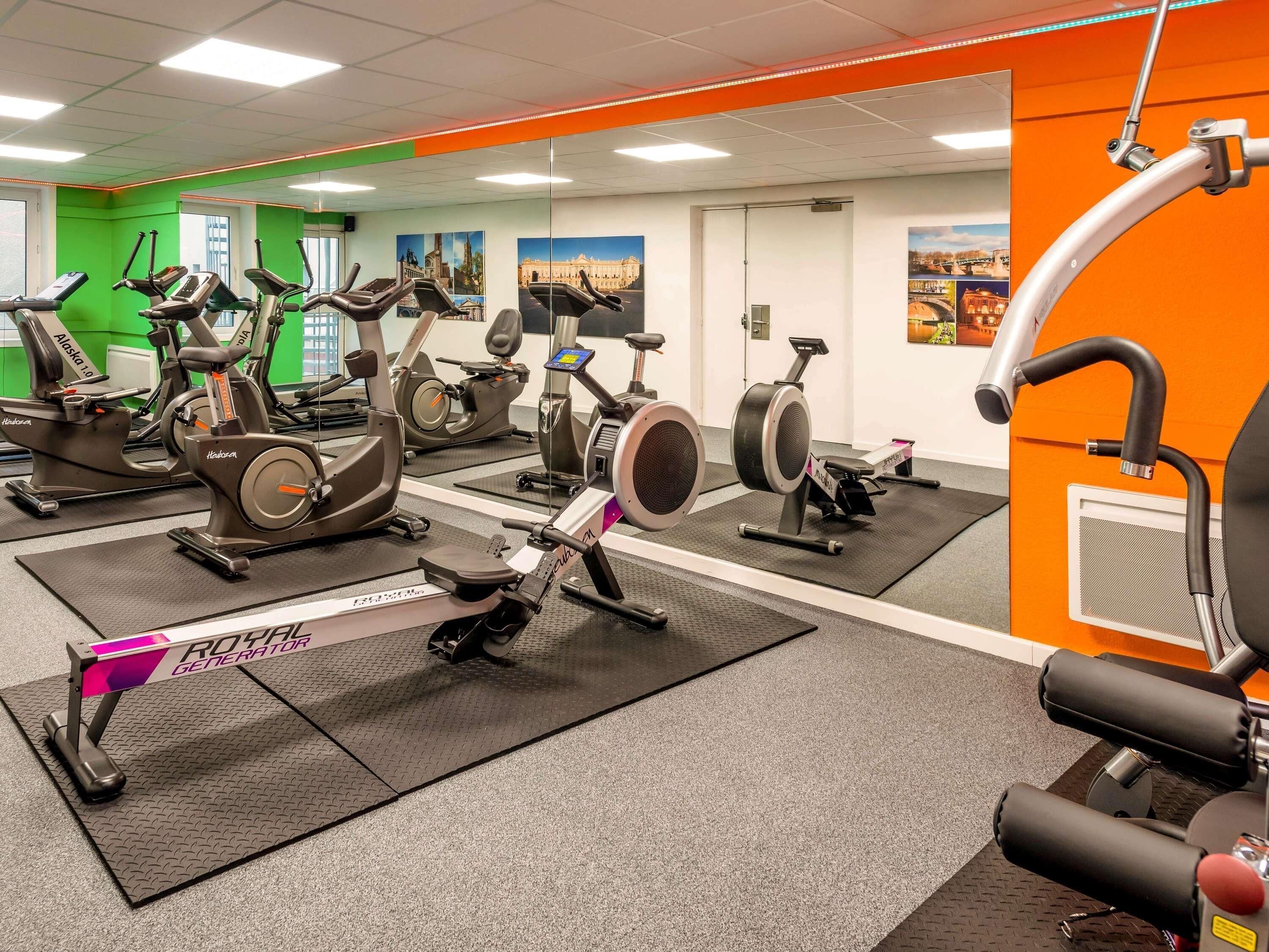 Un gimnasio con bicicletas estáticas, cintas de correr y una máquina de remo.