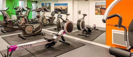 Un gimnasio con bicicletas estáticas, cintas de correr y una máquina de remo.