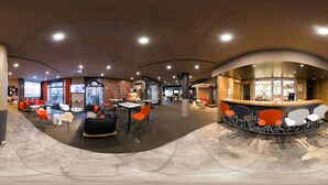 A modern lounge area with seating arrangements, a bar, and a large window providing natural light.