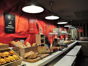 Zona de bufé con pan, bollería y salsas.