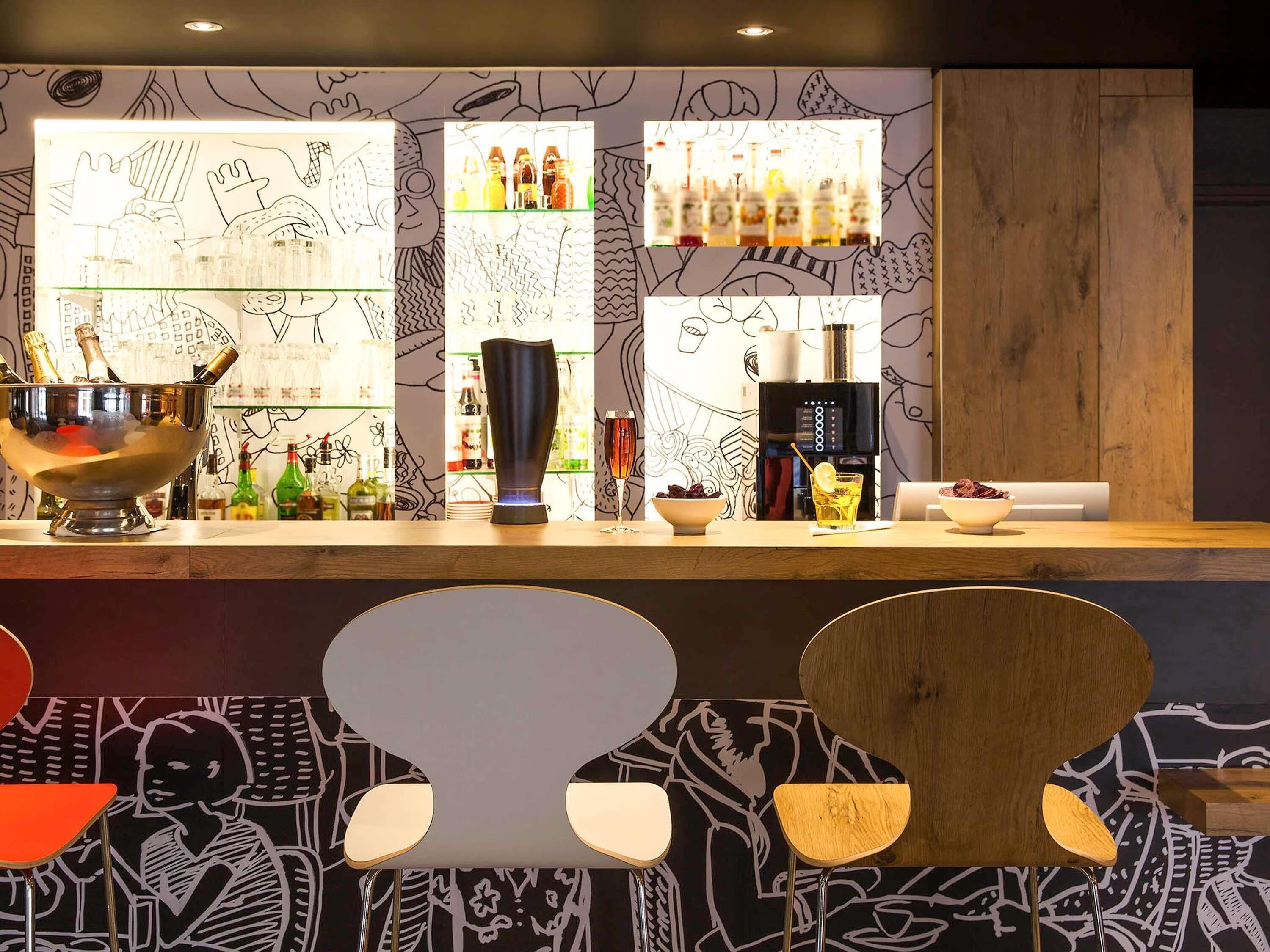 A bar area with a counter, bar stools, and a wall with abstract patterns.