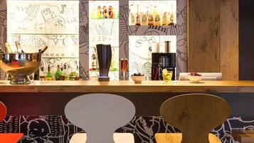 Zona de bar con mostrador, taburetes y pared con diseños abstractos.