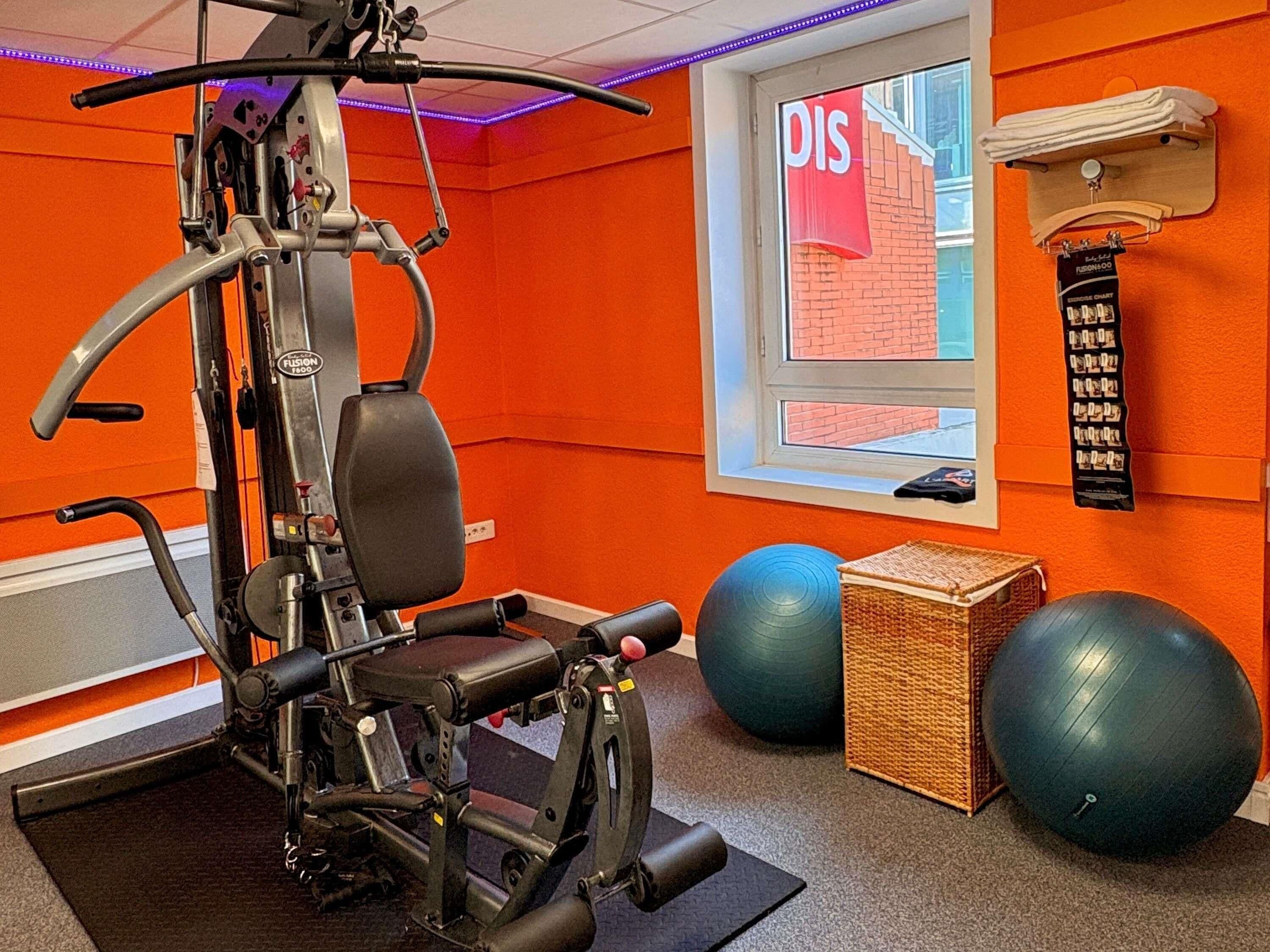 A gym with exercise equipment, a window with a 'DIS' sign, and exercise balls.