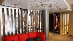 A modern interior with a red sofa, a white coffee table, and a decorative ceiling with architectural drawings.