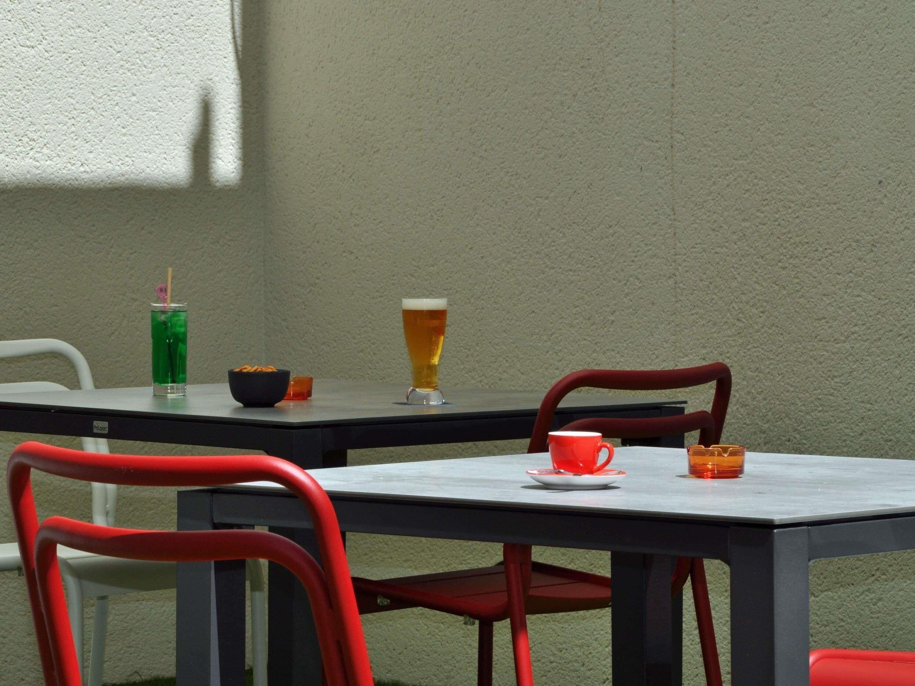A table with a glass of beer, a red cup, and a bowl of snacks.