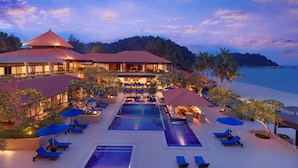 Un resort con piscina, sillas de descanso y vista a la playa.