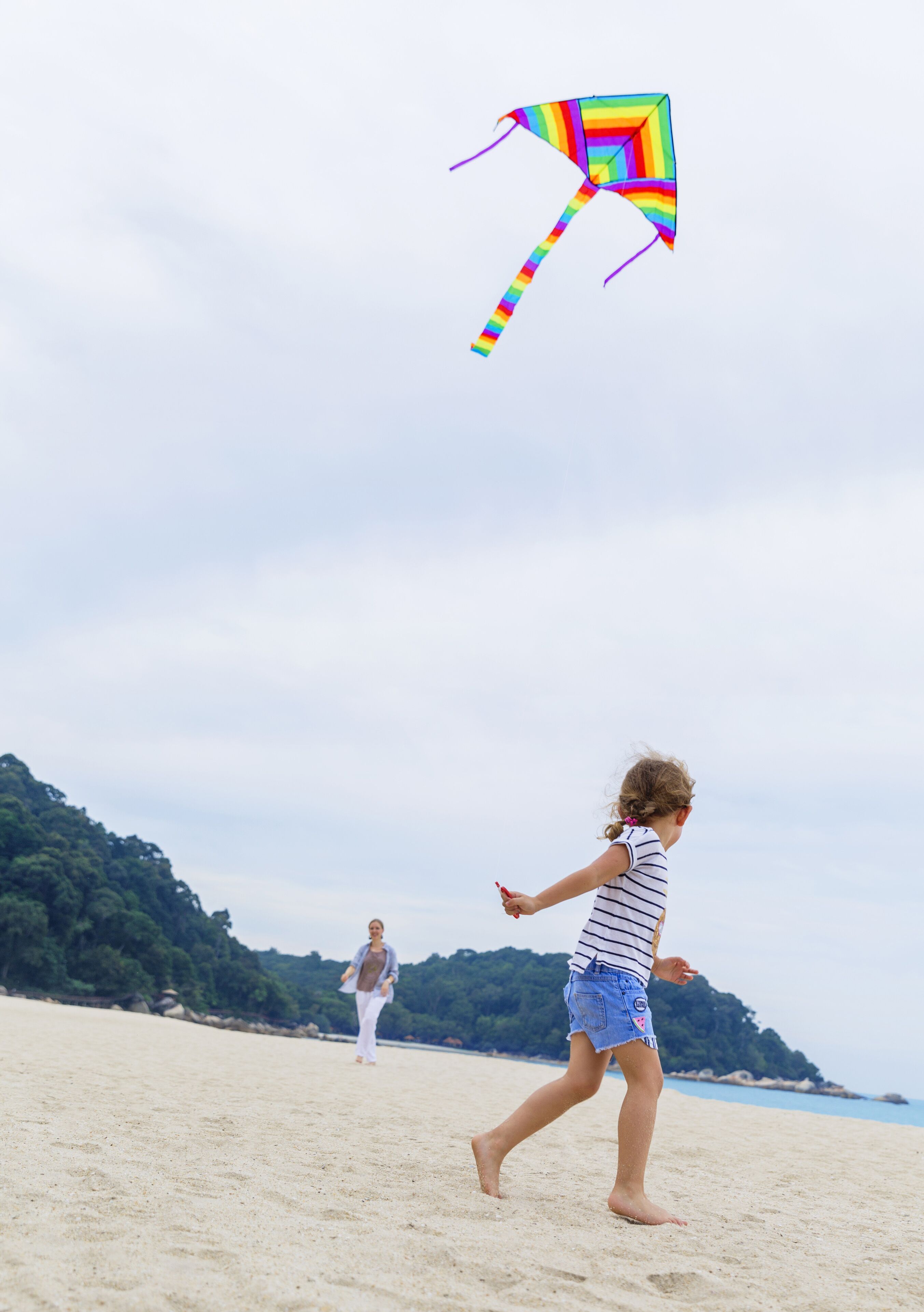 A beach scene with a child flying a kite.