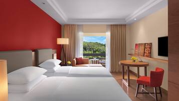 A hotel room with two beds, a dining table, a TV, and a view of a forest.