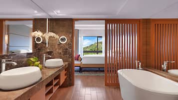 A modern bathroom with a large bathtub, two sinks, and a vanity with a mirror.