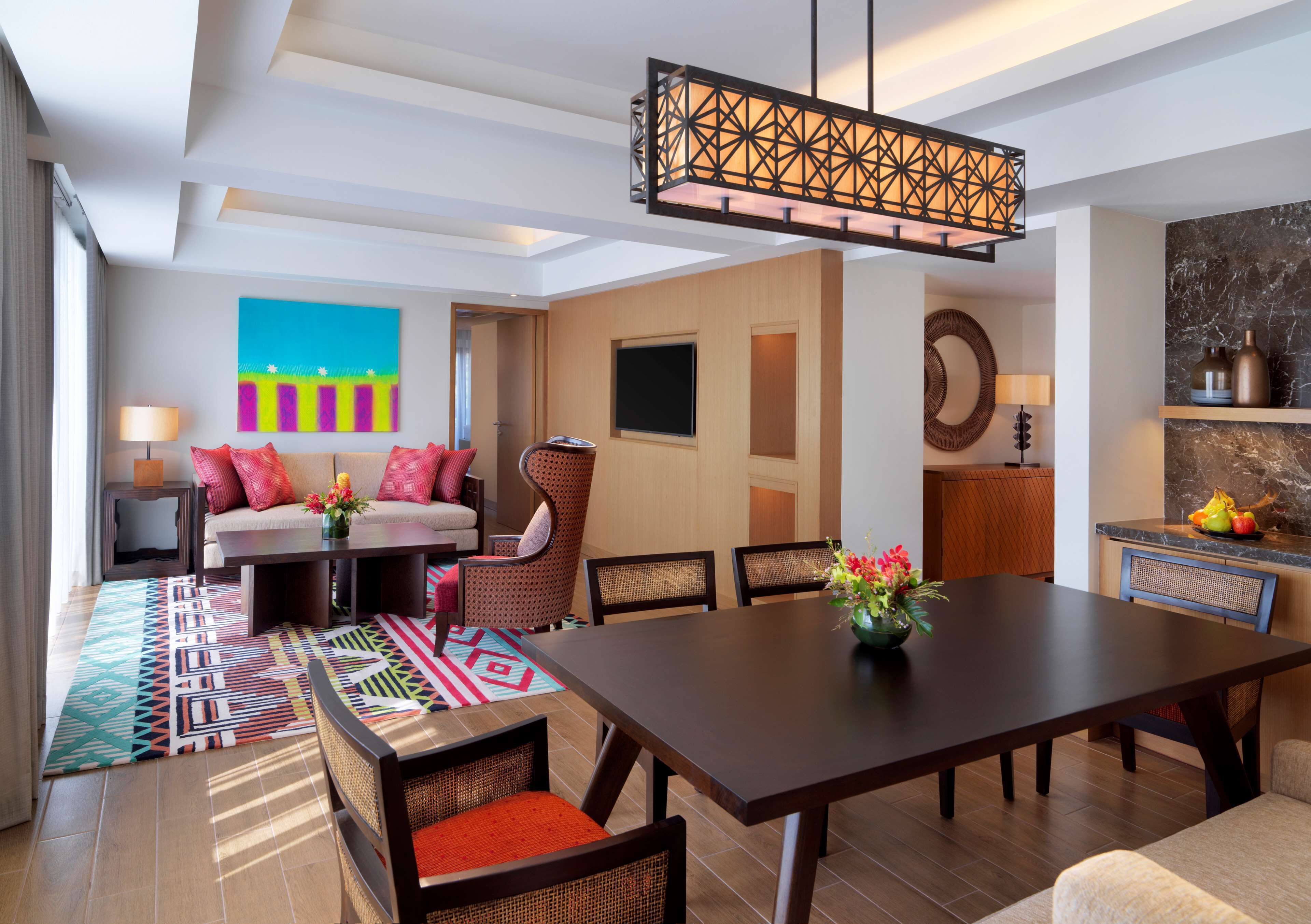 A modern dining area with a large table, chairs, and a hanging light fixture.