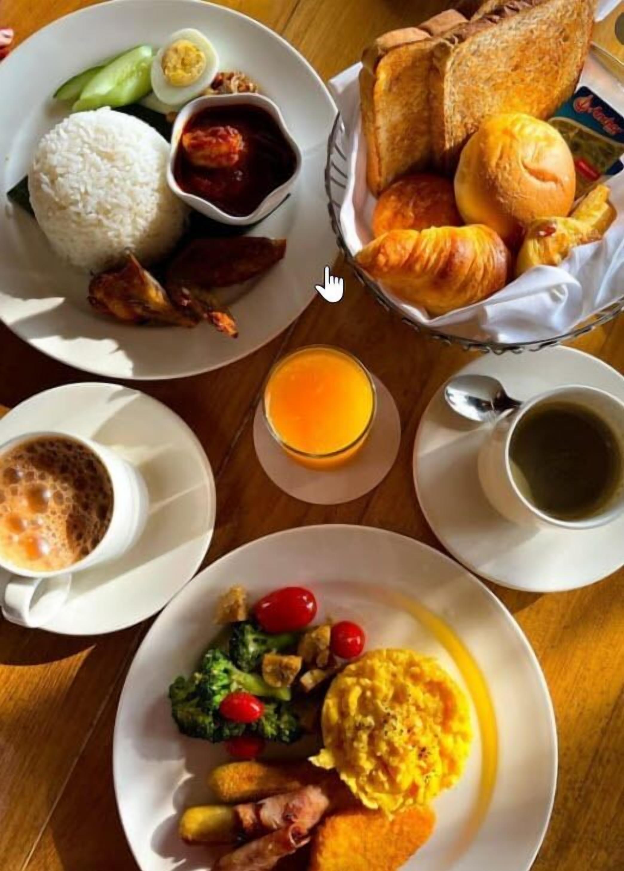 A breakfast setting with plates of food, a basket of croissants, and two cups of coffee.