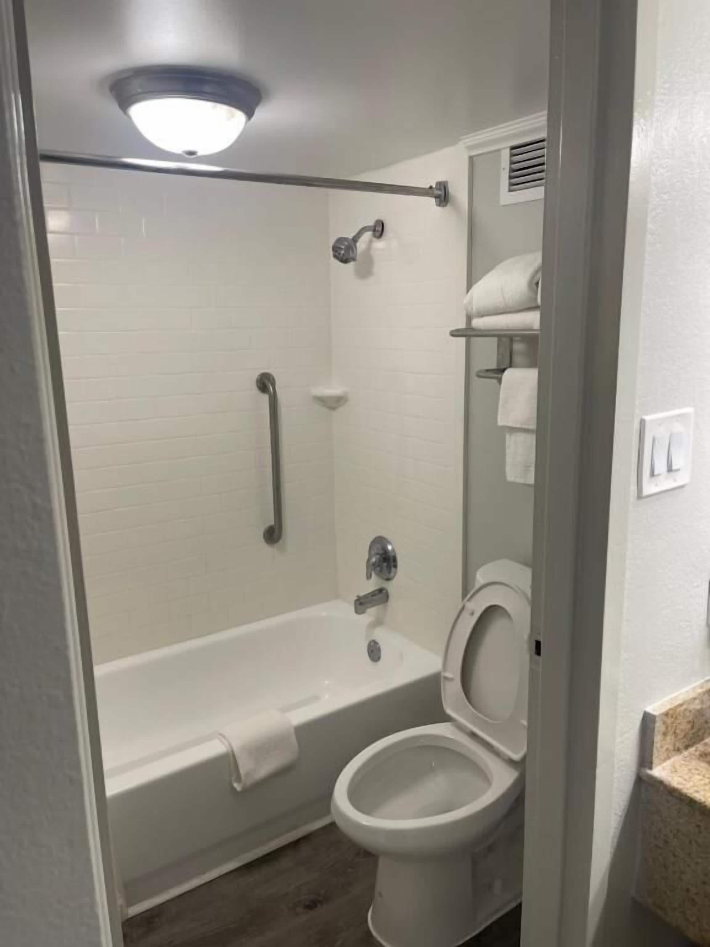 A bathroom with a bathtub, toilet, and a glass shower enclosure.