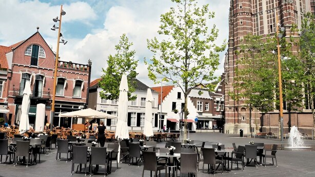 A square with outdoor seating, a tall brick building, and a fountain. - A-Hotel Oosterhout (Oosterhout)