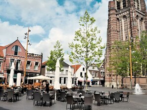 A square with outdoor seating, a tall brick building, and a fountain. - A-Hotel Oosterhout (Oosterhout)