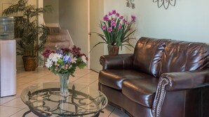 A living room with a glass coffee table, a brown leather sofa, and potted plants. - Days Inn by Wyndham San Marcos (San Marcos)