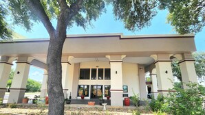 A building with a covered entrance, large windows, and a number '1005' on the facade. - Days Inn by Wyndham San Marcos (San Marcos)