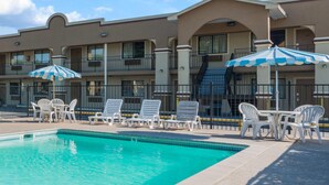 A hotel with a swimming pool, outdoor seating, and umbrellas. - Days Inn by Wyndham San Marcos (San Marcos)