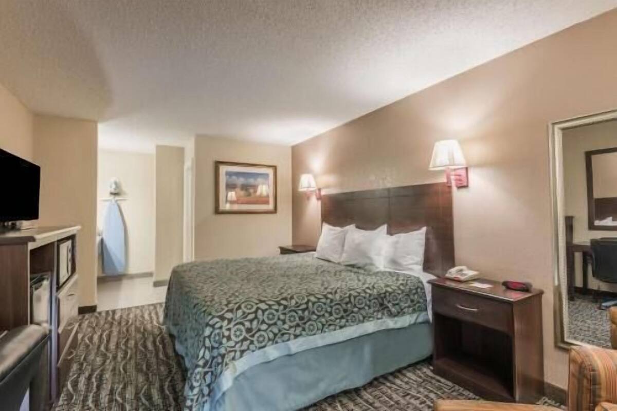 A hotel room with a bed, bedside table, lamp, and a television.