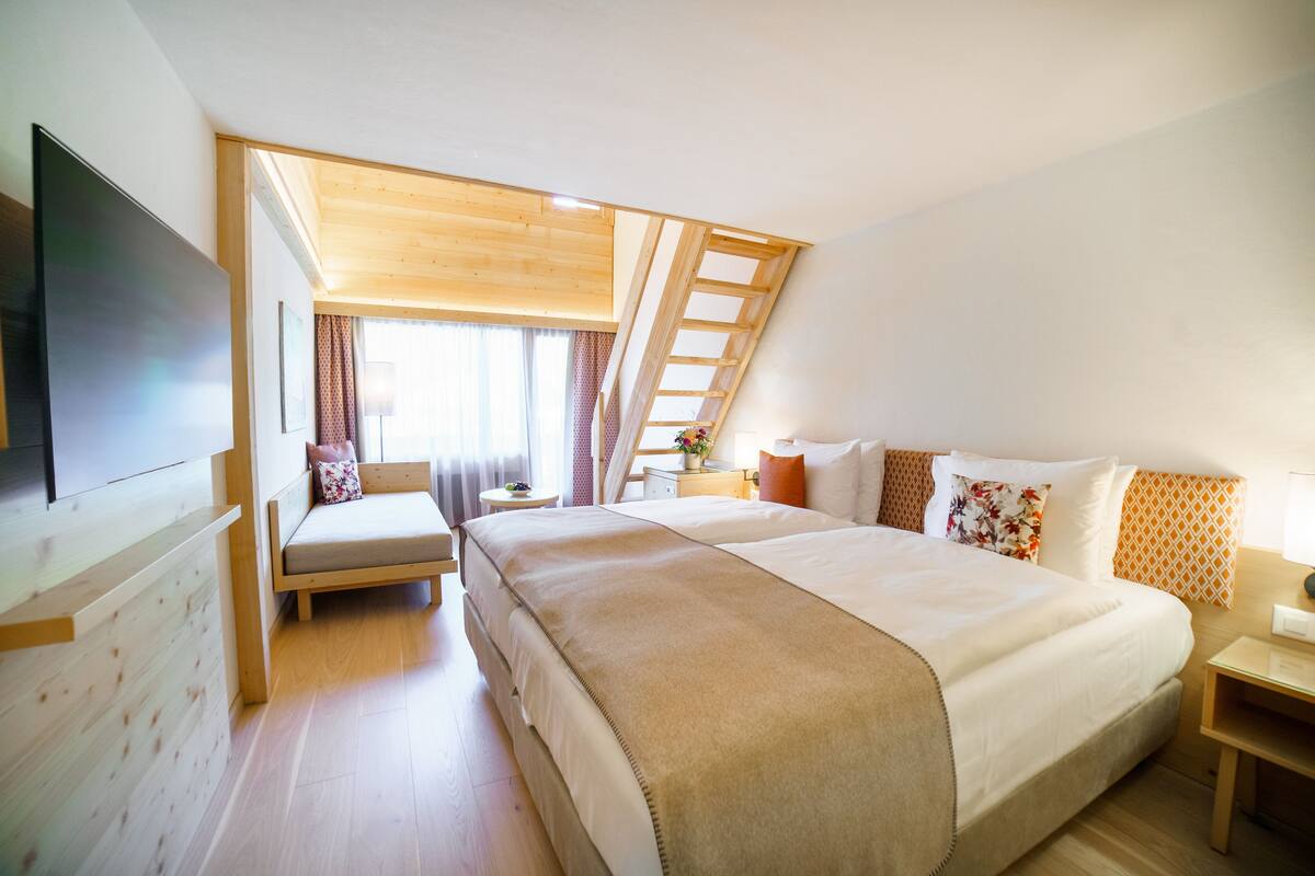 Une chambre d’hôtel moderne avec un grand lit, une télévision, un bureau et une fenêtre avec des rideaux.