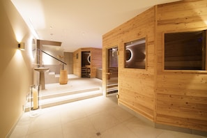 A modern interior with wooden paneling, a staircase, and a glass door leading to a dark room. - Gstaaderhof – Active & Relax Hotel  (Saanen)
