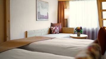 Ein Hotelzimmer mit zwei Betten, einem kleinen runden Tisch mit Blumen in einer Vase, einer Lampe und einem Gemälde an der Wand.