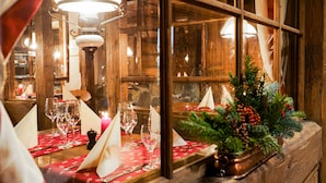 A wooden interior with a table set for dining, a decorative pine branch, and a lit lamp. - Gstaaderhof – Active & Relax Hotel  (Saanen)