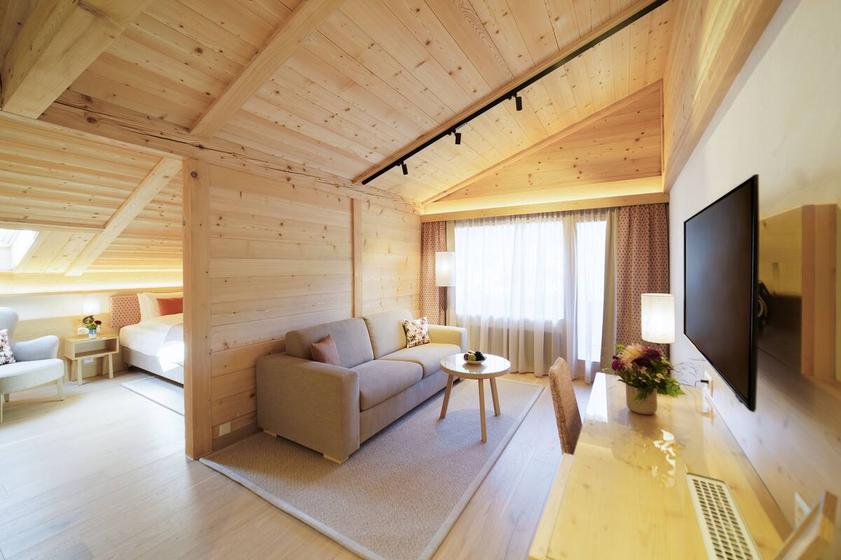 Une cabane moderne en rondins de bois, avec un intérieur en bois, un canapé, une table basse, un téléviseur et un bureau avec une lampe.
