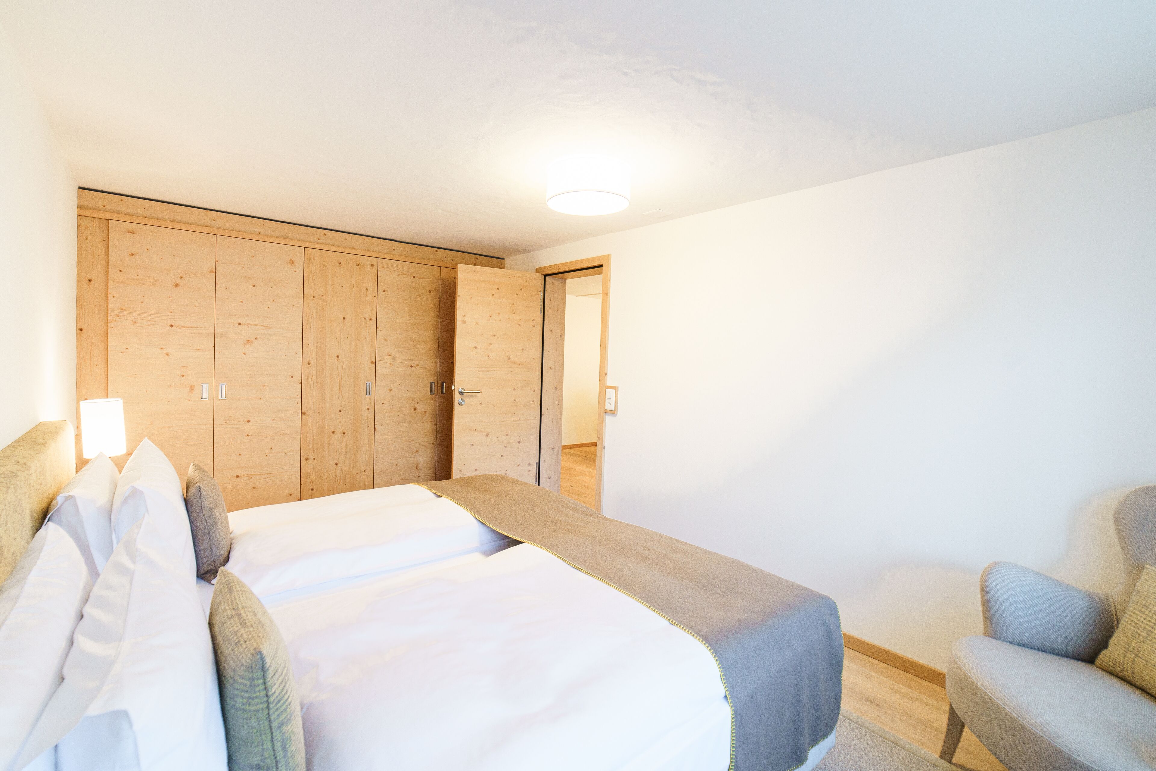 Un dormitorio con una cama, una silla y armarios de madera.