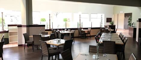 A spacious restaurant with multiple tables and chairs, large windows, and a clean, modern interior.