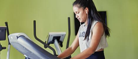 A person using a treadmill in a room with green walls.