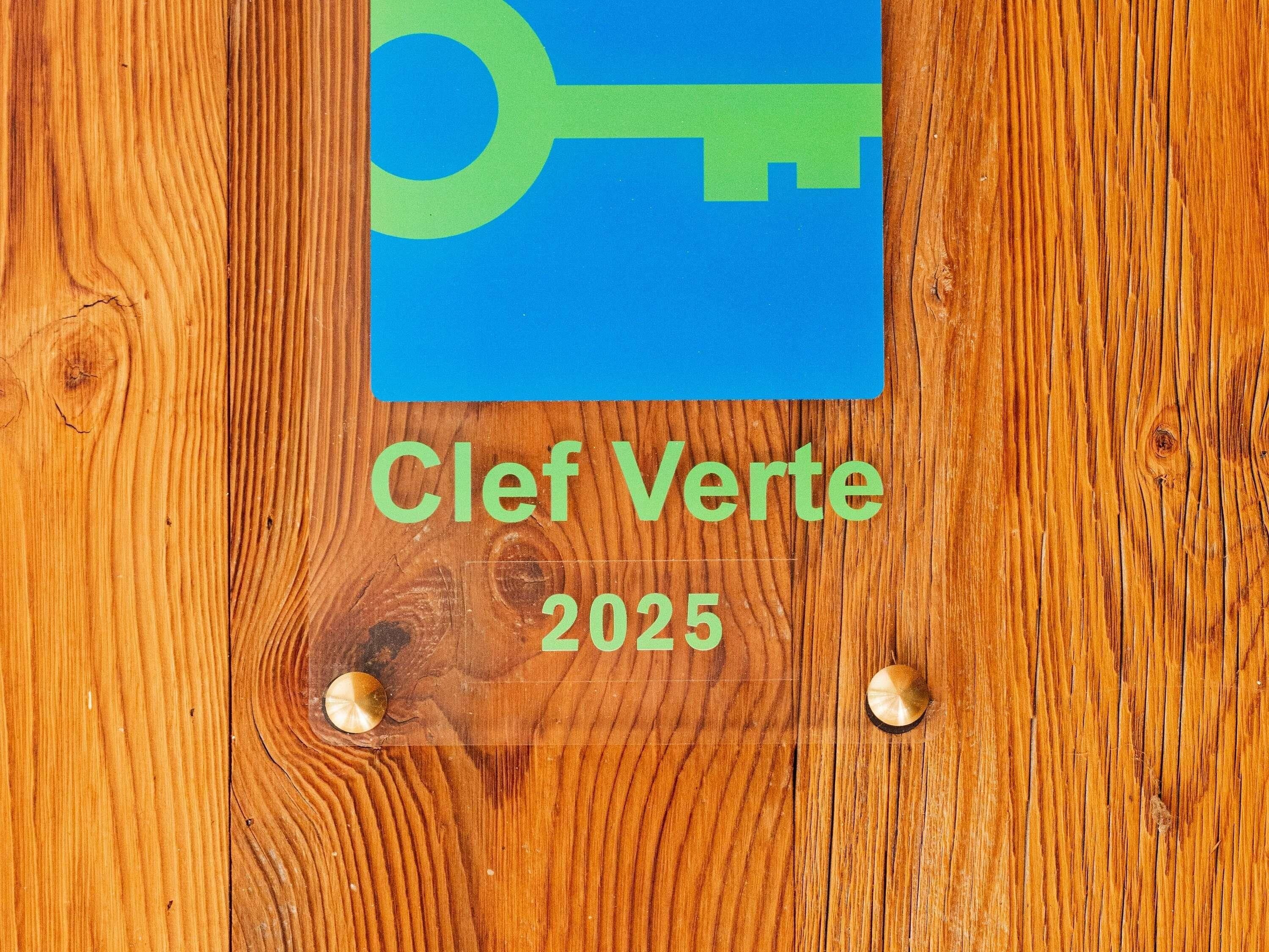 A wooden surface with a blue sign featuring a keyhole and the text "Clef Verte 2025".