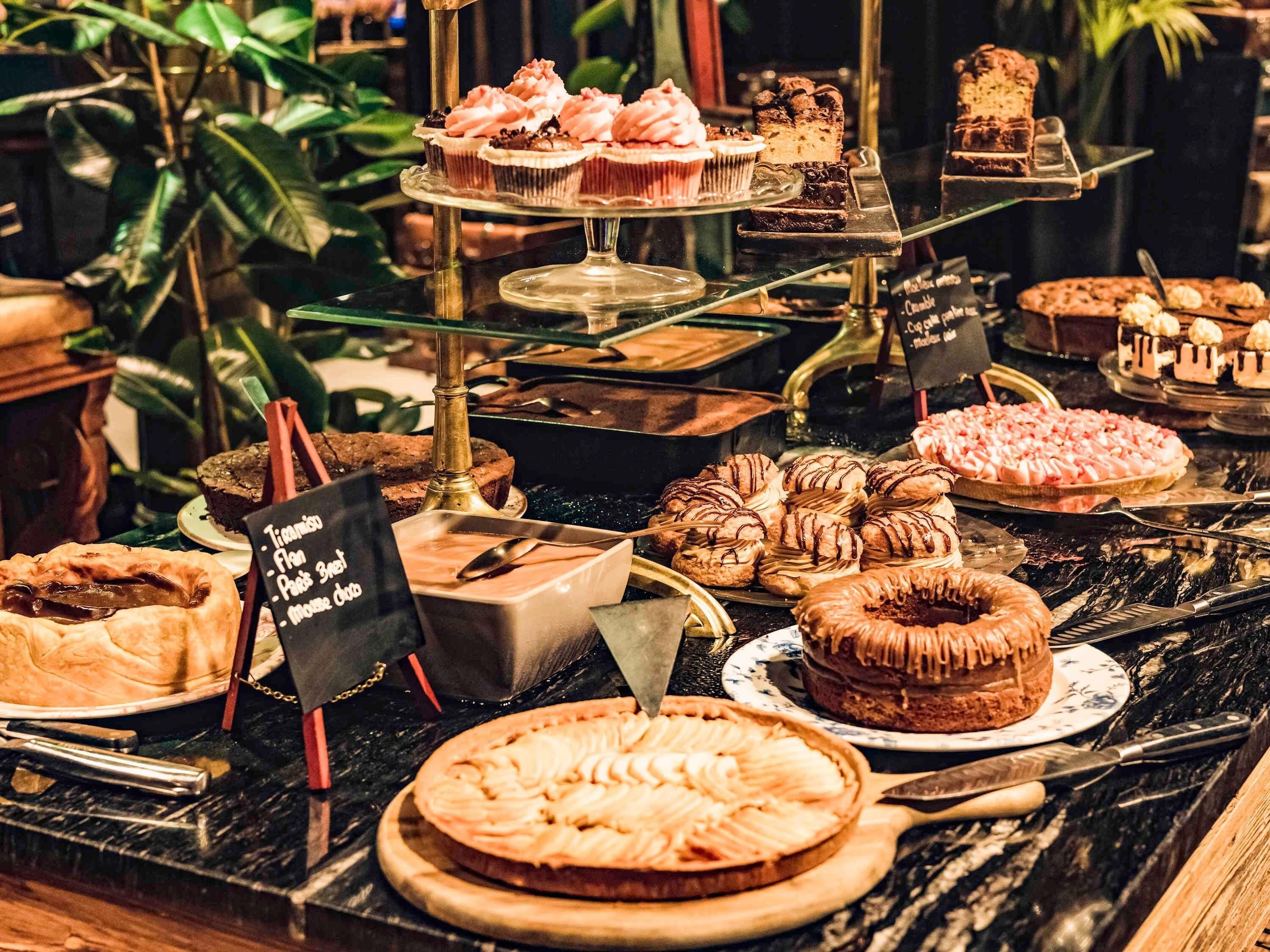 Een dessertpresentatie met diverse gebakjes en taarten op een marmeren toonbank.