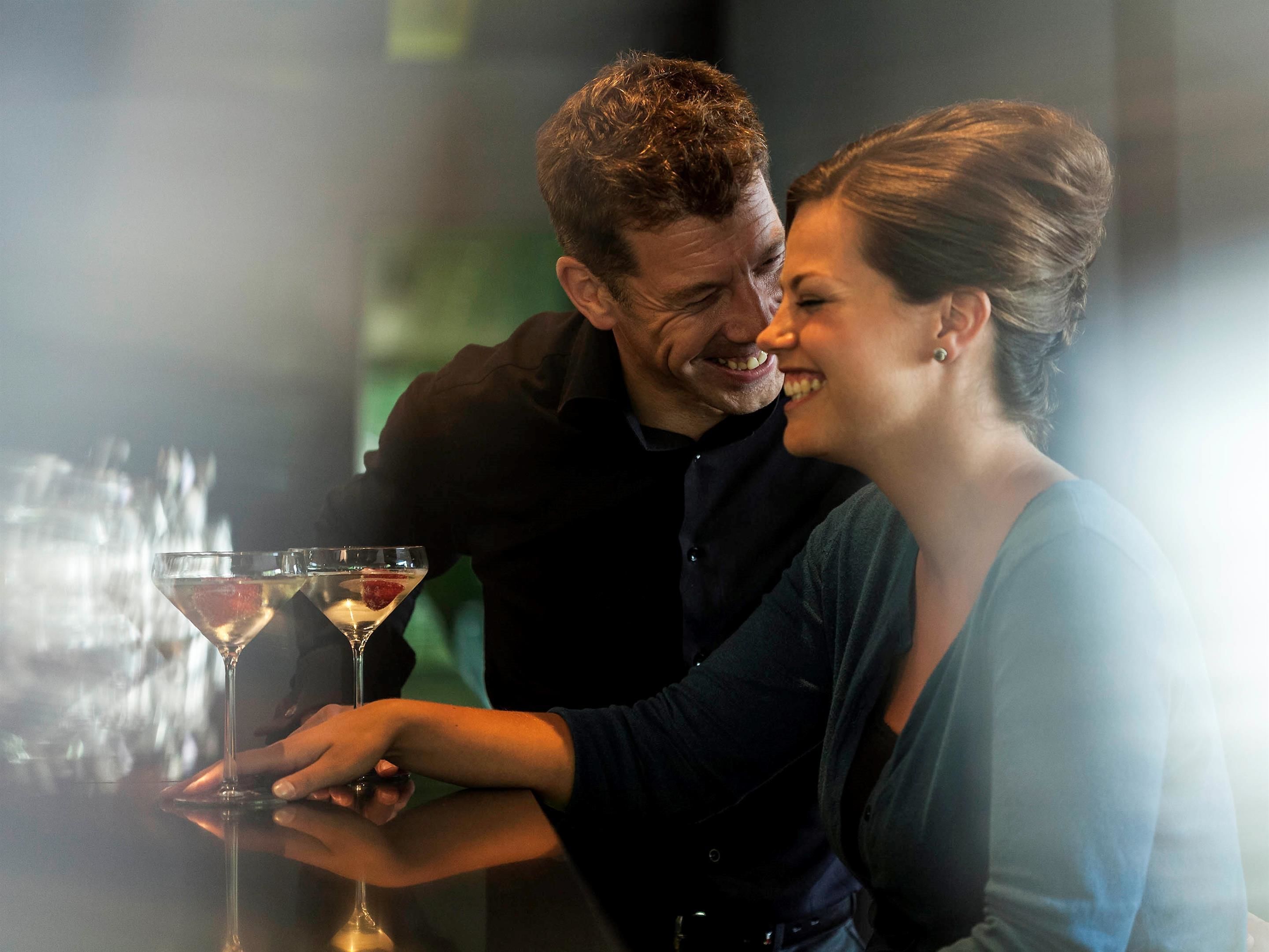 A couple at a bar with a martini glass.