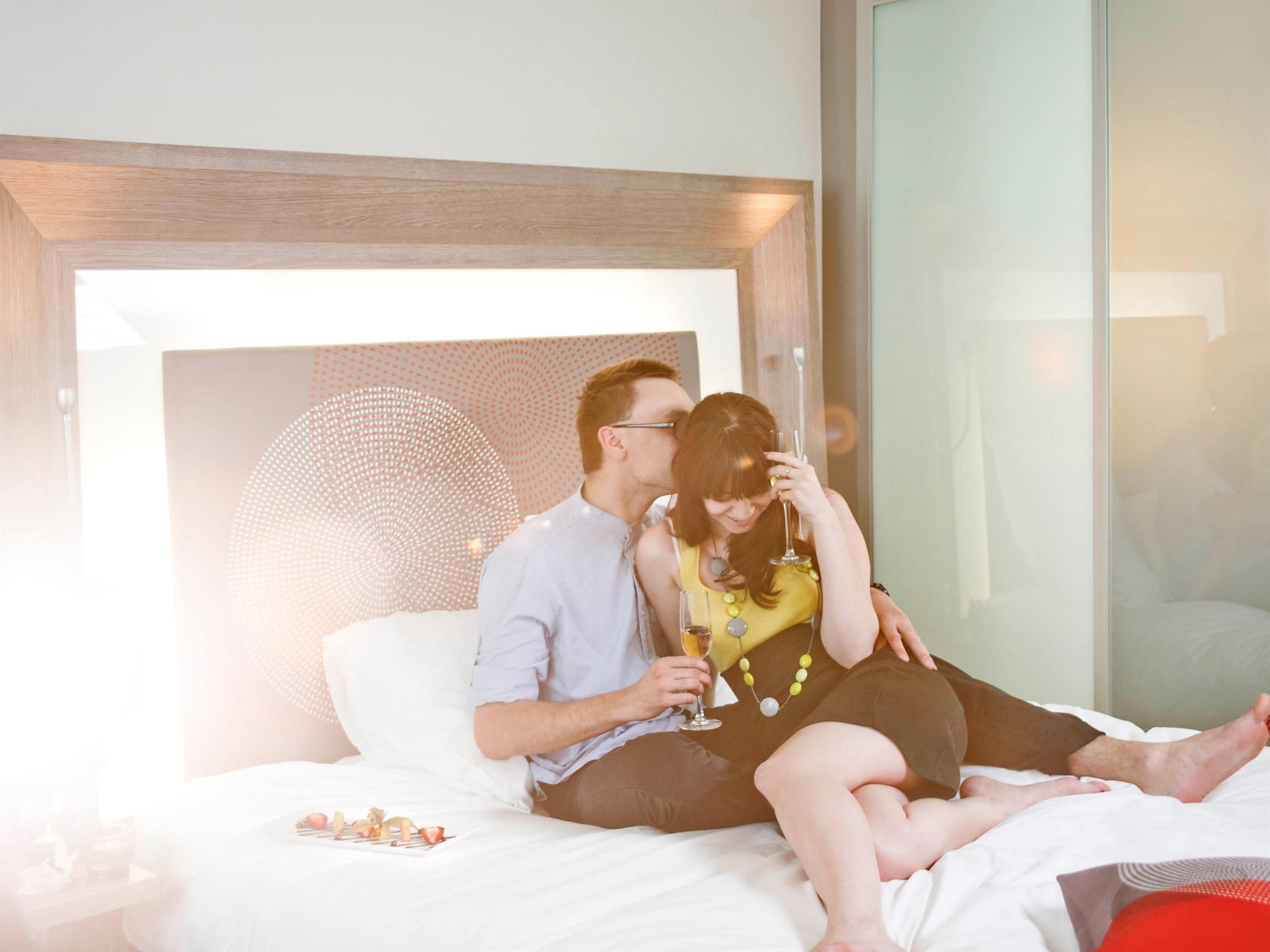 Une chambre d’hôtel avec un lit, une table de chevet et un mur en verre.