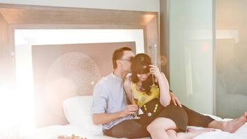 Une chambre d’hôtel avec un lit, une table de chevet et un mur en verre.