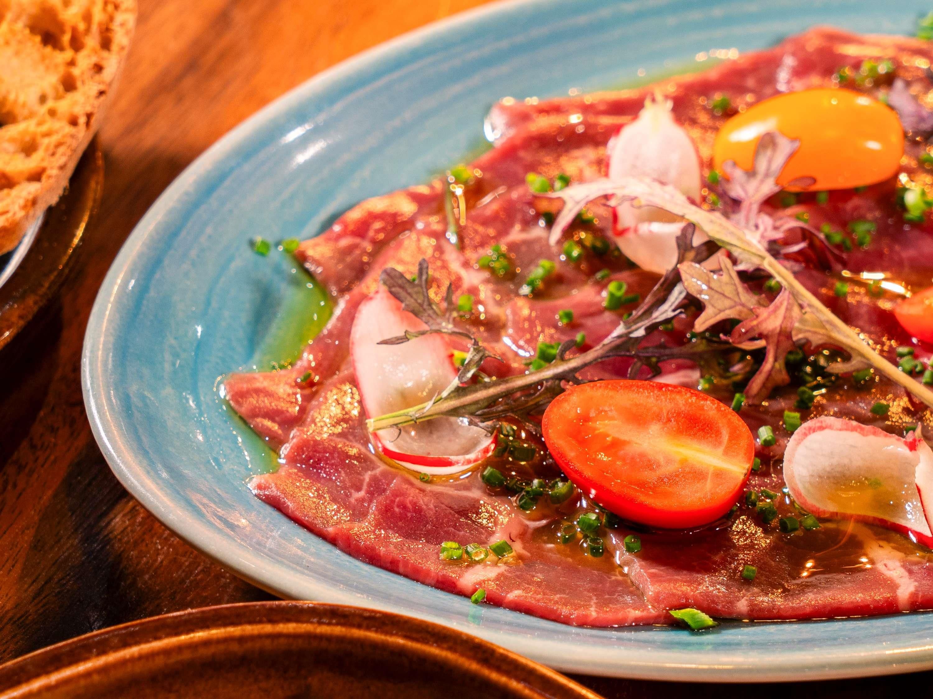 Ein Teller mit rohem Fleisch, Gemüse und Kräutern.