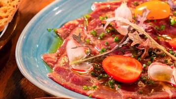 Ein Teller mit rohem Fleisch, Gemüse und Kräutern.