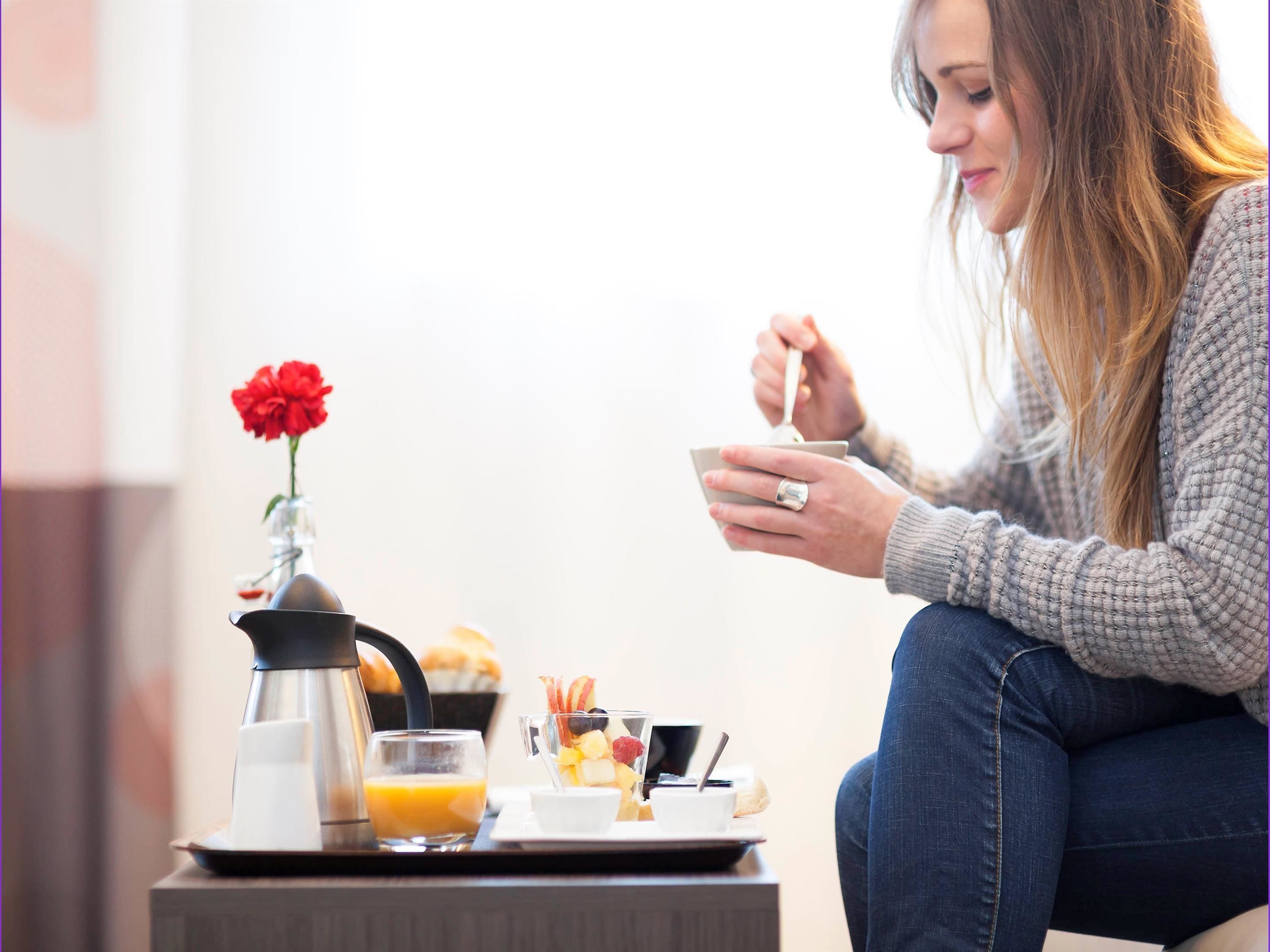 A breakfast setup with a coffee pot, a glass of orange juice, a plate with toast and a cup of coffee, and a flower vase.