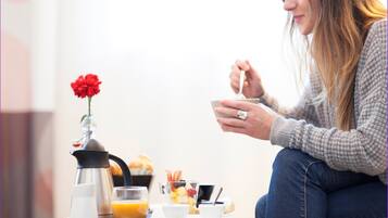 A breakfast setup with a coffee pot, a glass of orange juice, a plate with toast and a cup of coffee, and a flower vase.