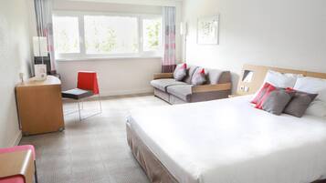 Habitación de hotel con una cama grande, un escritorio, una silla, un sofá y una ventana con cortinas.