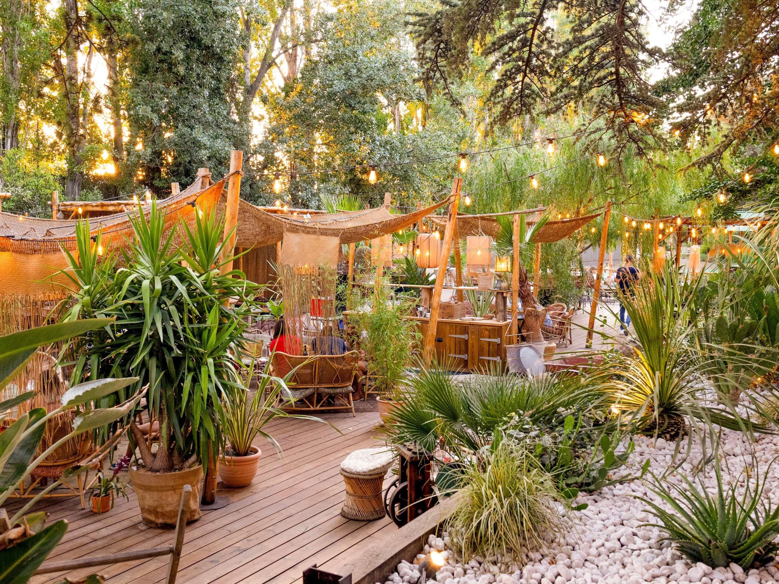 An outdoor patio area with wooden furniture, potted plants, and string lights.