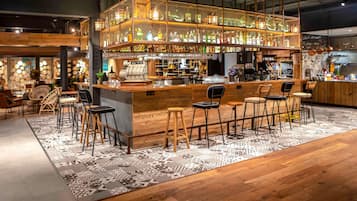 Zona de bar con mostrador de madera, taburetes y una alfombra estampada.
