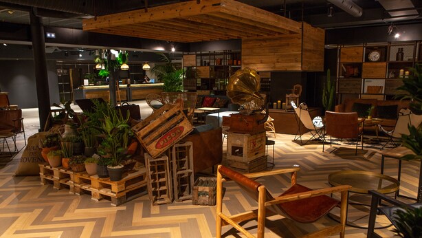 A cozy, rustic interior with wooden furniture, a herringbone floor, and a variety of plants. - Novotel Avignon Nord (Sorgues)