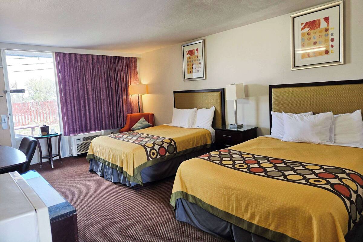 A hotel room with two beds, a desk, and a chair.