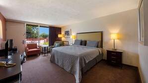 A hotel room with a bed, desk, chair, and a small table. - Travelodge by Wyndham Oakley (Oakley)