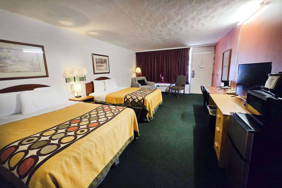 A hotel room with two beds, a desk with a computer, a TV, and a chair.