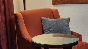 A room with a red armchair, a grey pillow, a small glass table, and a floor lamp. - Travelodge by Wyndham Oakley (Oakley)