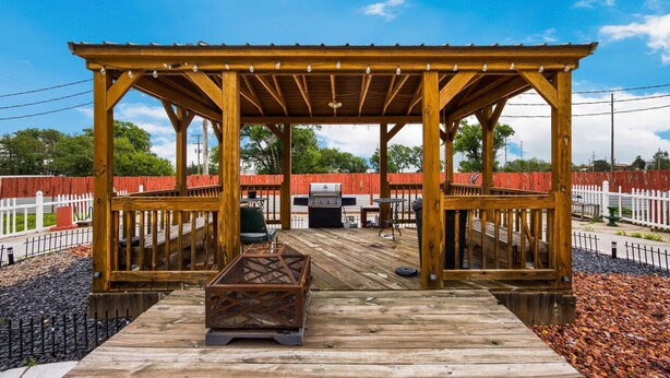 A wooden deck with a pergola, barbecue grill, and outdoor seating area. - Travelodge by Wyndham Oakley (Oakley)
