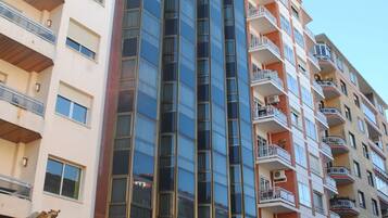 Un hotel de varios pisos con fachada de vidrio moderna, balcones y un cartel visible que dice 'Hotel Ascut'.
